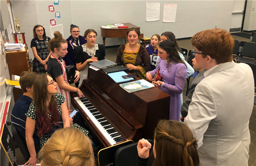 Students around a piano running lines for the play